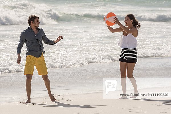 Glückliches junges Paar beim Spielen mit einem Strandball