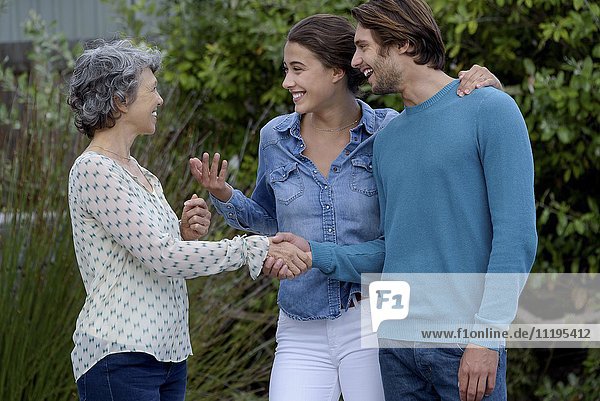 Happy mature woman meet with young couple outside