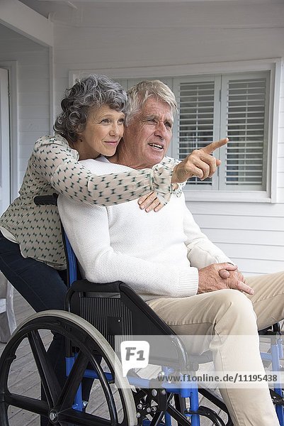 Senior man in wheelchair with his wife on porch