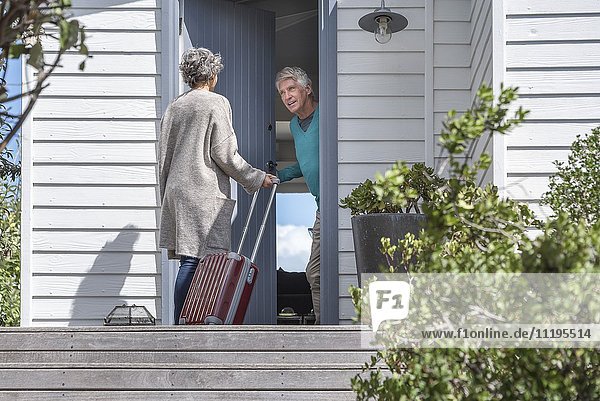 Senior man welcoming woman at doorway