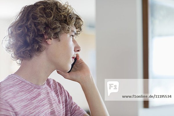 Teenager-Junge spricht zu Hause auf dem Handy