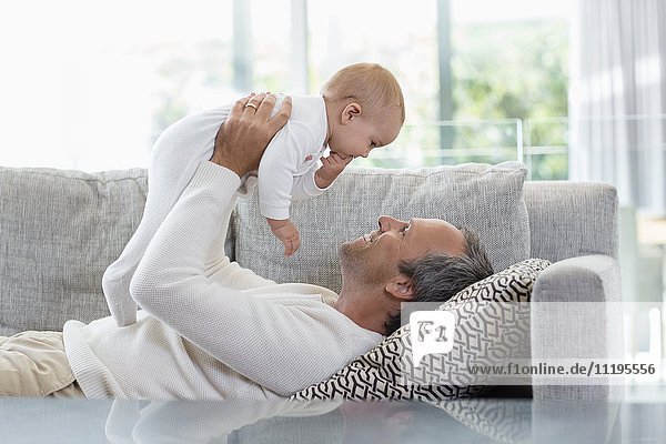 Happy father playing with his cute baby daughter at home