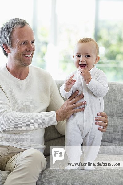 Happy father playing with his cute baby daughter in living room