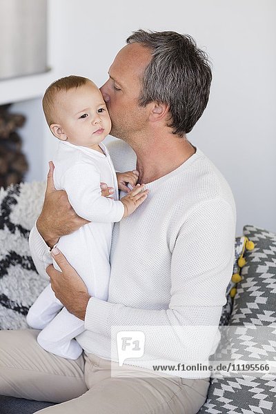Vater küsst seine süße kleine Tochter im Wohnzimmer