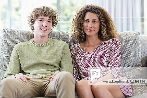 Porträt einer glücklichen Mutter und eines glücklichen Sohnes auf der Couch im Wohnzimmer