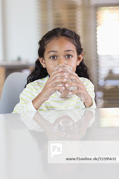Little girl drinking a glass of water at home
