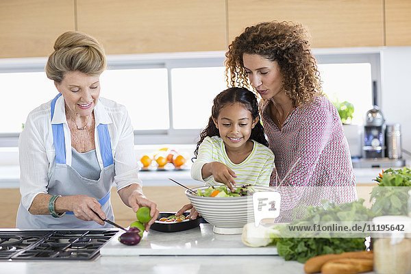 Senior woman with daughter and granddaughter preparing food in kitchen