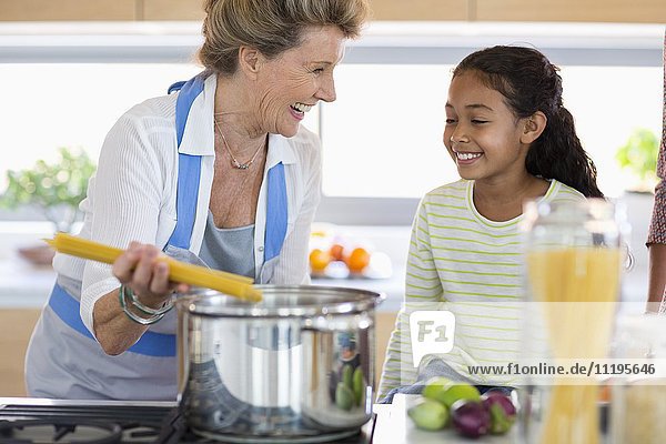 Fröhliche Seniorin mit Enkelin bei der Zubereitung des Essens in der Küche