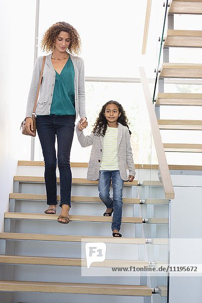 Glückliche Mutter und Tochter halten sich an der Treppe.