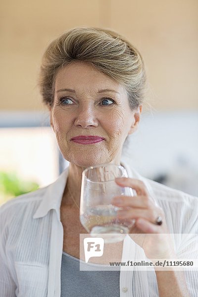 Glückliche Seniorin mit einem Glas Wasser.