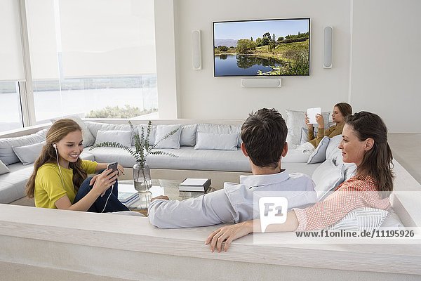 Couple watching television with their children busy in different activities