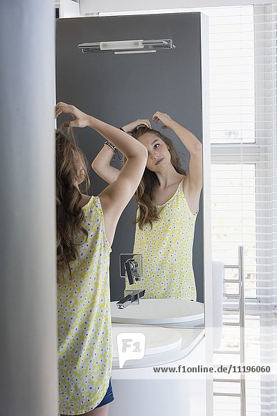 Teenage girl examining her hair in mirror
