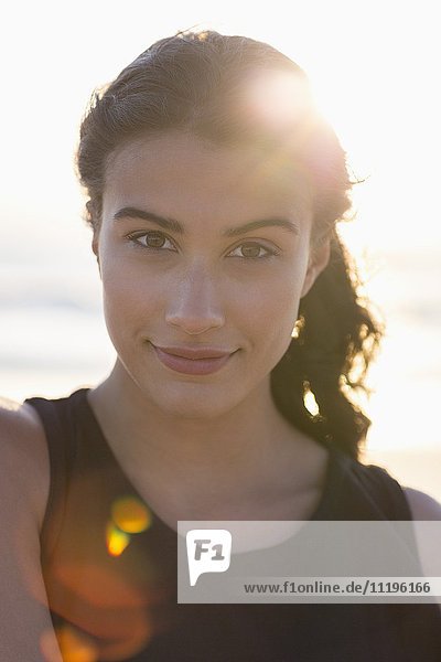 Porträt einer glücklichen jungen Frau am Strand stehend