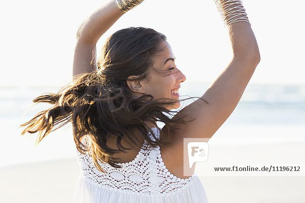Fröhliche junge Frau  die am Strand posiert.