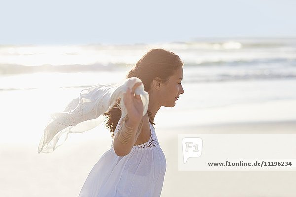Fröhliche junge Frau genießt am Strand