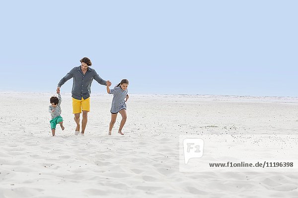 Ein Mann mit seinen Kindern am Strand.