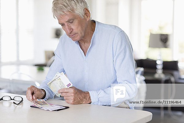 Senior man counting currency note son table
