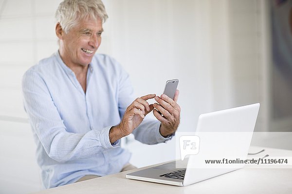 Happy Senior Mann fotografiert Laptop-Bildschirm mit Kamera-Handy