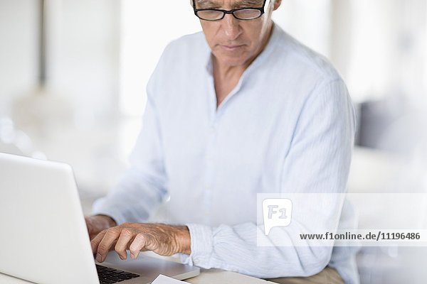 Senior man paying bills online on laptop
