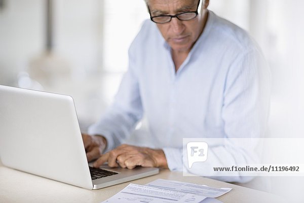 Senior Mann bezahlt Rechnungen online auf dem Laptop