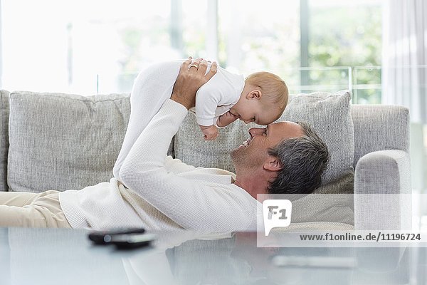 Happy father playing with his cute baby daughter at home