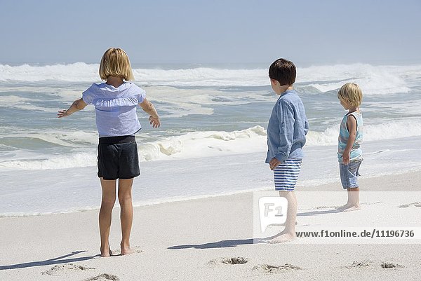 Drei Kinder am Strand stehend
