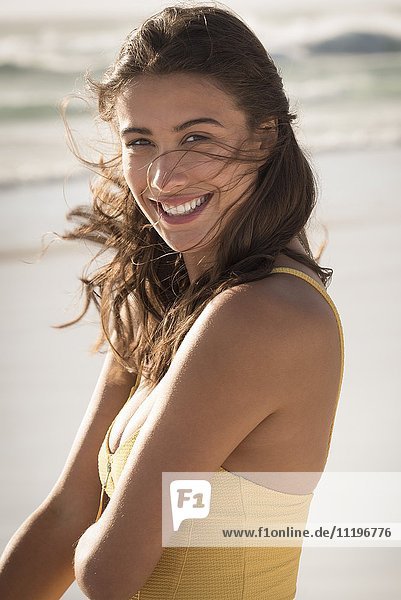 Fröhliche junge Frau am Strand stehend