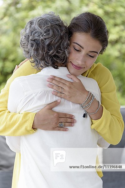 Liebevolle Mutter umarmt ihre erwachsene Tochter.