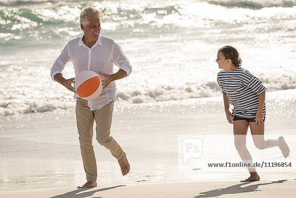 Glücklicher Großvater spielt mit Enkelin am Strand
