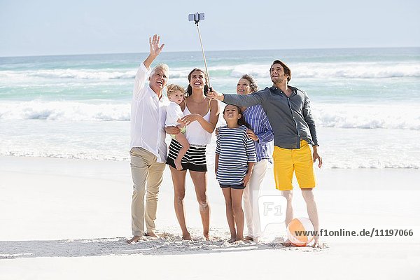 Mehrgenerationen-Familie  die am Strand steht und Selfie nimmt.