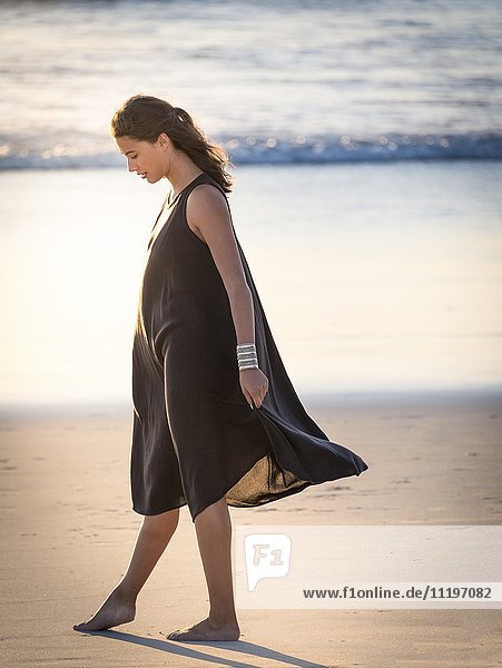 Schöne junge Frau  die am Strand spazieren geht.