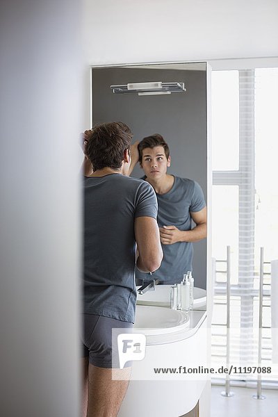 Junger Mann überprüft sein Haar im Spiegel
