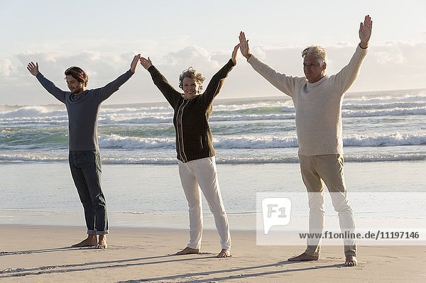 Happy family practicing yoga on the beach