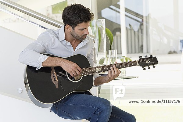 Mittlerer Erwachsener Mann beim Gitarrespielen