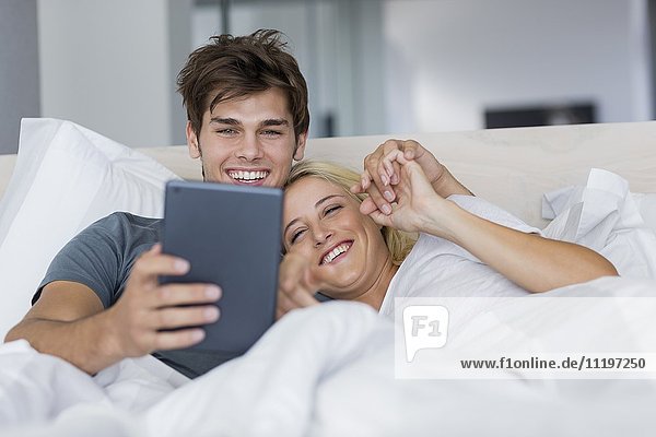 Ein glückliches junges Paar schaut sich einen Film auf einem digitalen Tablett an.