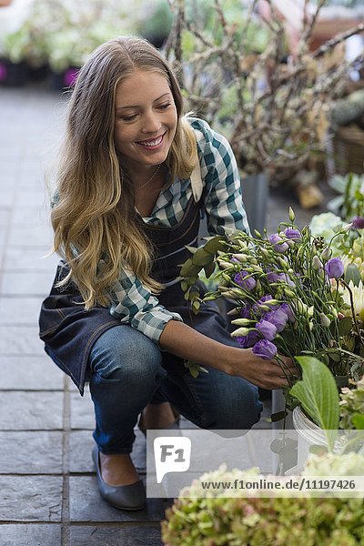 Glückliche Frau schaut Blumen in ihrem Geschäft an