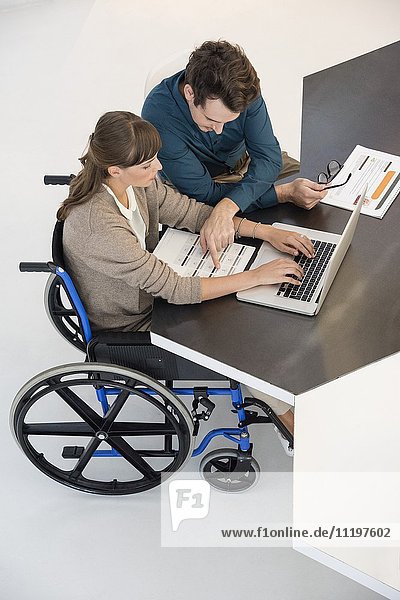 Zwei Geschäftsleute  die in einem Büro an einem Laptop arbeiten.
