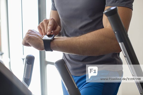 Midsection view of a man using smart watch in a gym