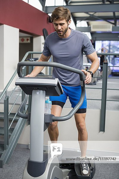 Mann trainiert die Beine mit einem Widerstand Gewicht Maschine in der Turnhalle
