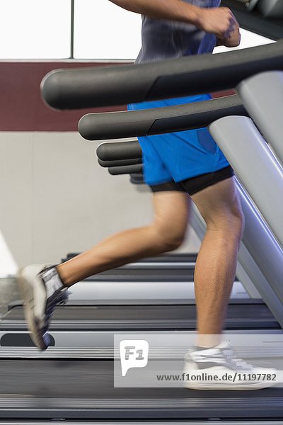 Low section view of a man running on a treadmill