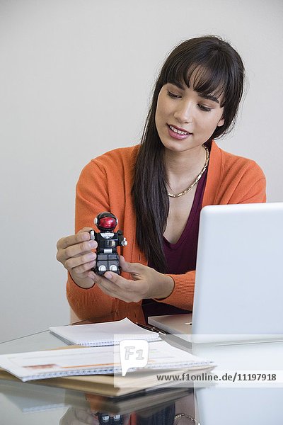 Geschäftsfrau beim Spielen mit einem Spielzeugroboter im Büro