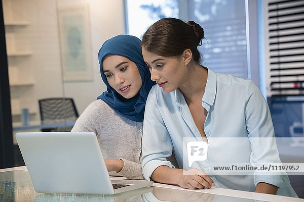 Two businesswomen looking at a laptop in an office
