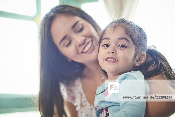 Hispanic mother holding smiling daughter