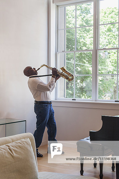 Mann spielt Saxophon in der Nähe des Fensters