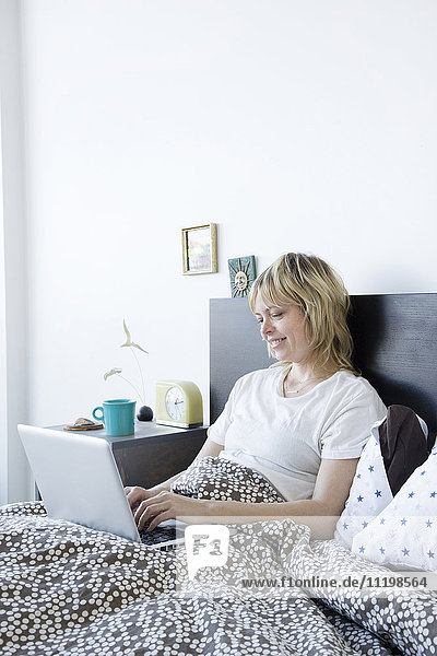 Caucasian woman using laptop in bed