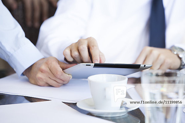 Geschäftsleute diskutieren über die Arbeit mit dem digitalen Tablett bei Kaffee