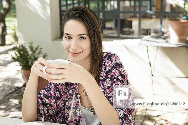 Junge Frau genießt eine Tasse Kaffee im Freien
