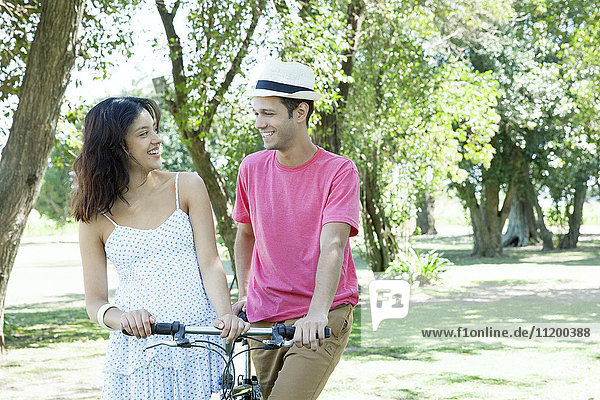 Young couple walking bicycle together