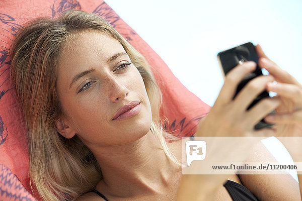 Woman relaxing on lounge chair using smartphone