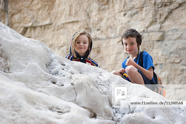 Kinder hocken auf dem Felsen